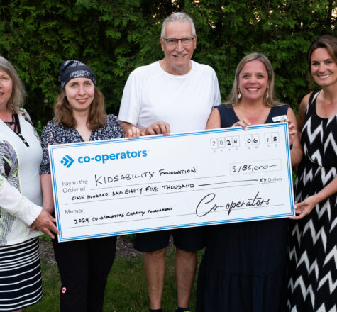 five individuals hold an oversized cheque that demonstrates the philanthropy of an insurance company.